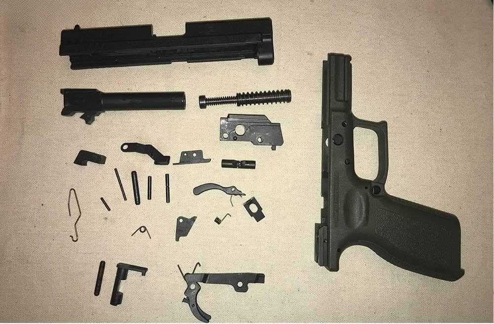 A Springfield Armory XD handgun disassembled into several pieces DURING firearm destruction.